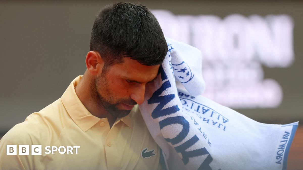 Novak Djokovic reacts during the Italian Open, raising a towel to his face while wearing a yellow tennis shirt