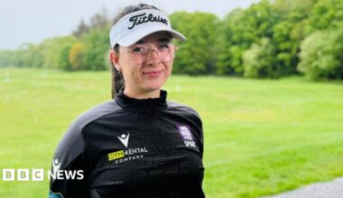 Amateur golfer Robyn Fowlie smiling at the camera at a golf driving range, she is wearing a branded golf hat.
