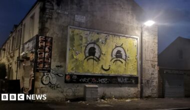 A billboard decorated with a large billboard, showing large eyes on a yellow face, similar to Spongebob Squarepants