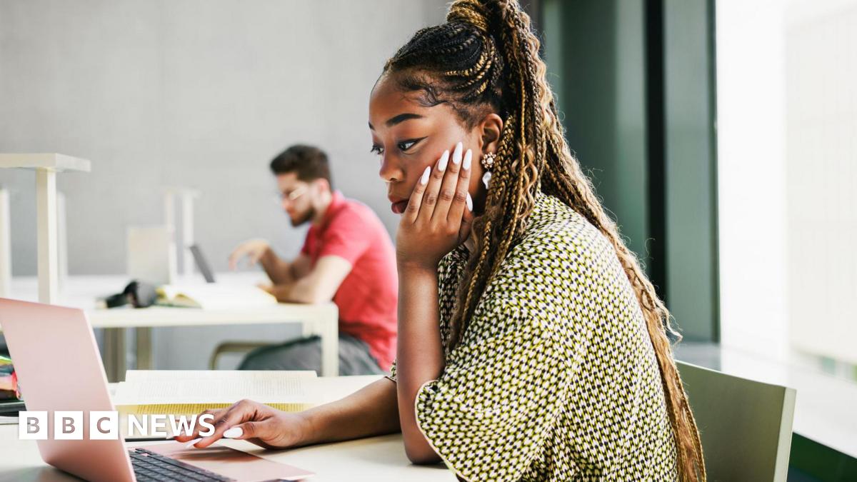 A young woman working from a laptop in an modern office.