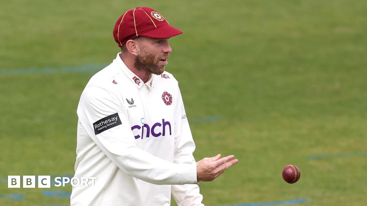 Luke Procter throws a red cricket ball to an unpictured player
