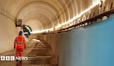A man in hi-vis clothing, branded with the logo of HS2, walks through the Chilterns tunnel