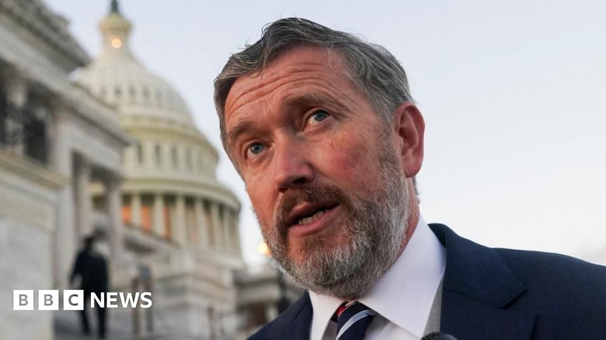 Gallrein wears a yellow tie and suit with a sign behind him saying "America First Works"