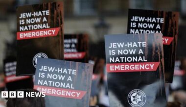 People hold up placards during a protest organized by the 'Campaign Against Antisemitism' outside Downing Street in London, Britain, 30 April 2026. The signs are black and red and read "JEW-HATE IS NOW A NATIONAL EMERGENCY".