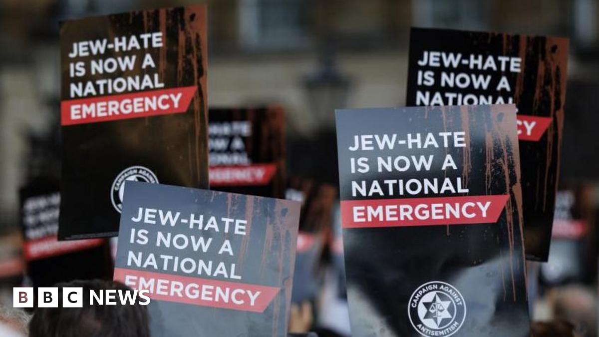 People hold up placards during a protest organized by the 'Campaign Against Antisemitism' outside Downing Street in London, Britain, 30 April 2026. The signs are black and red and read "JEW-HATE IS NOW A NATIONAL EMERGENCY".