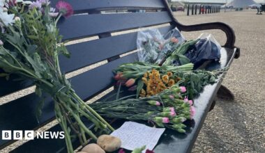 Bouquets of flowers on a bench with a hand-written note.