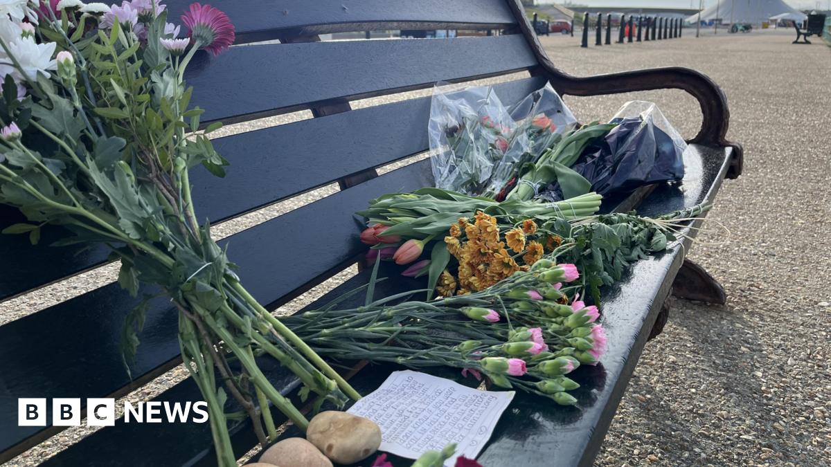 Bouquets of flowers on a bench with a hand-written note.