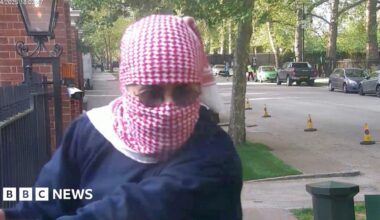 Abdullah Albadri, his head wrapped in a red and white traditional Arabic scarf, holding onto the railings at the Israeli embassy and looking in the direction of diplomatic protection officers - who are out of shot - and who are about to arrest him.
