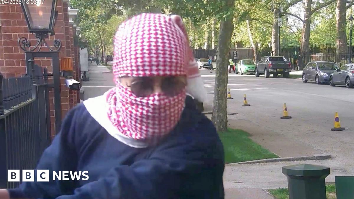 Abdullah Albadri, his head wrapped in a red and white traditional Arabic scarf, holding onto the railings at the Israeli embassy and looking in the direction of diplomatic protection officers - who are out of shot - and who are about to arrest him.