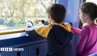 A boy and a girl look out the front window on the top level of a bus
