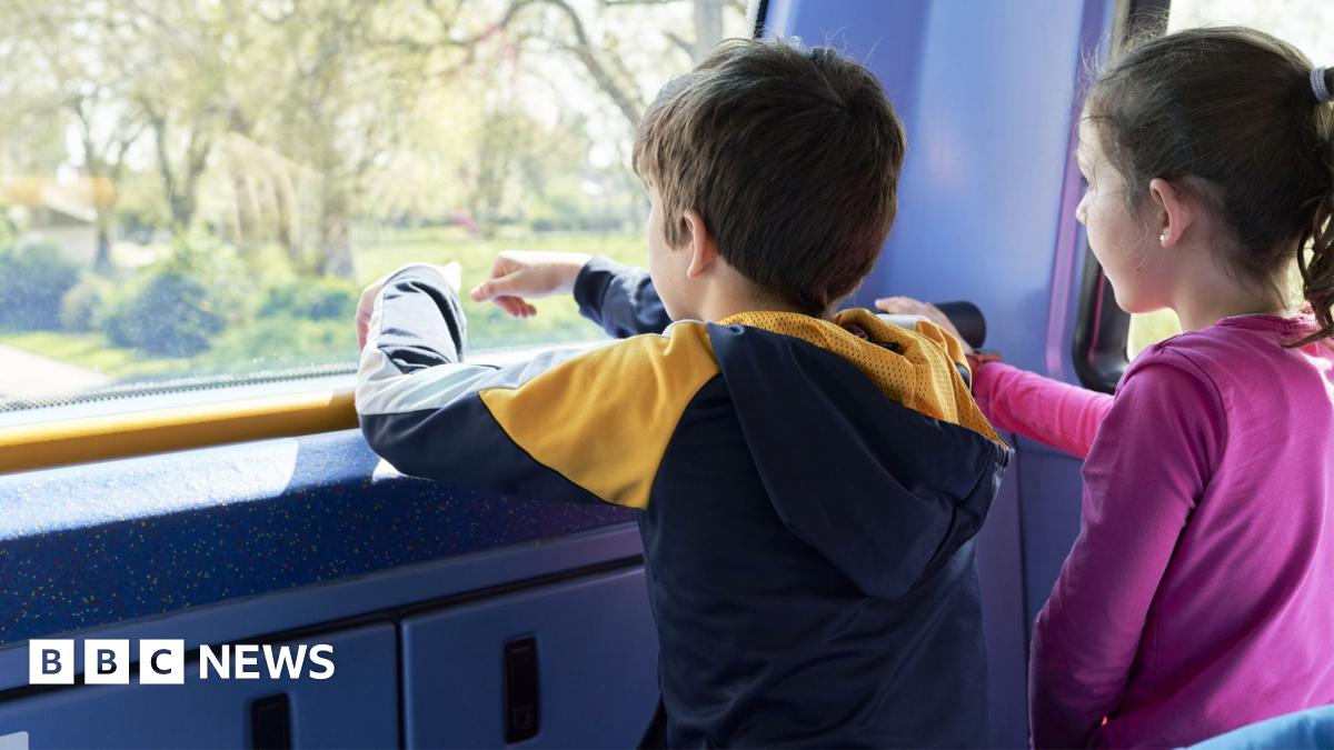 A boy and a girl look out the front window on the top level of a bus