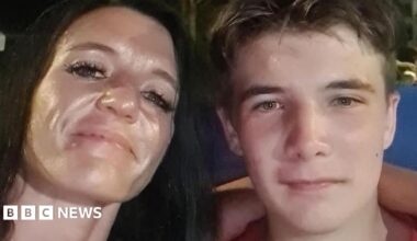 A close-up of Kirsten Coutts with her arm around her son, Sam. She has long black hair and he has short brown hair, both have the same coloured hazel eyes. They are smiling at the camera.