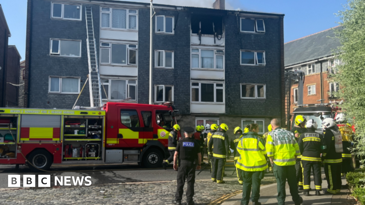 Firefighters at a block of flats, with a ladder against the building.