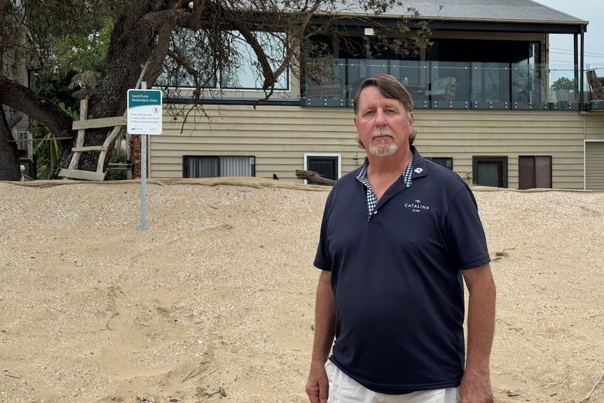 a man stands near to a sand dune
