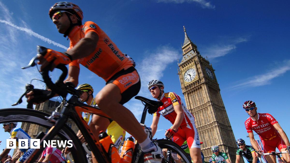 Cyclists in lycra and helmets travel past Big Ben, with blue skies in the background.