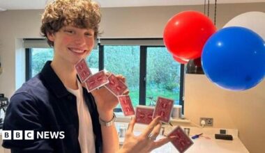 Rafferty in his kitchen smiling and holding playing cards between his fingers