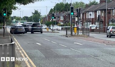 Image shows a police cordon in place on a main road, with tape surrounding several vehicles.
