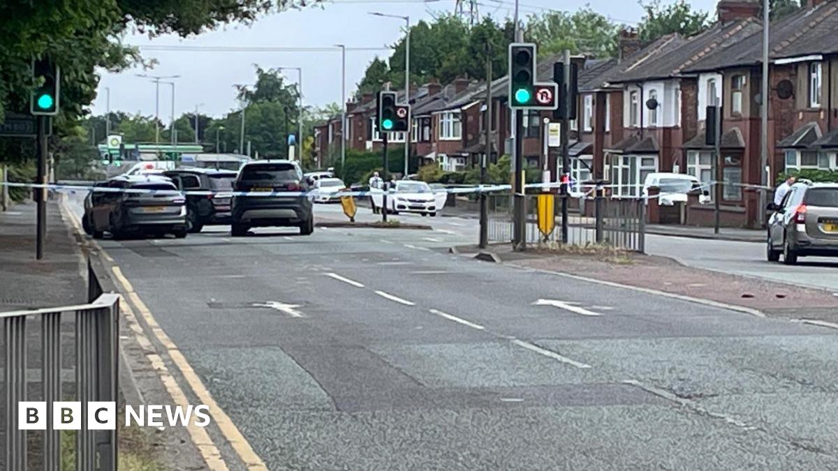 Image shows a police cordon in place on a main road, with tape surrounding several vehicles.