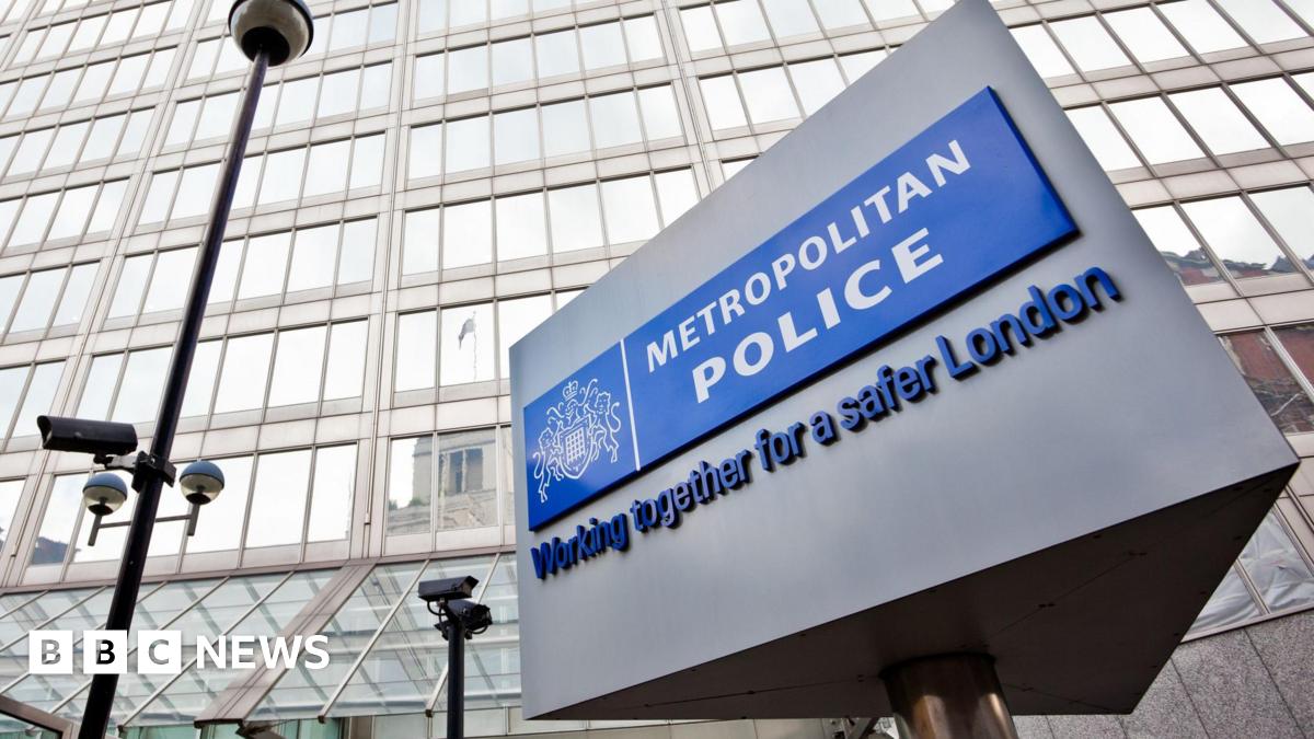 The well-known triangular Metropolitan Police sign is in the foreground of the image with the police headquarters in the background