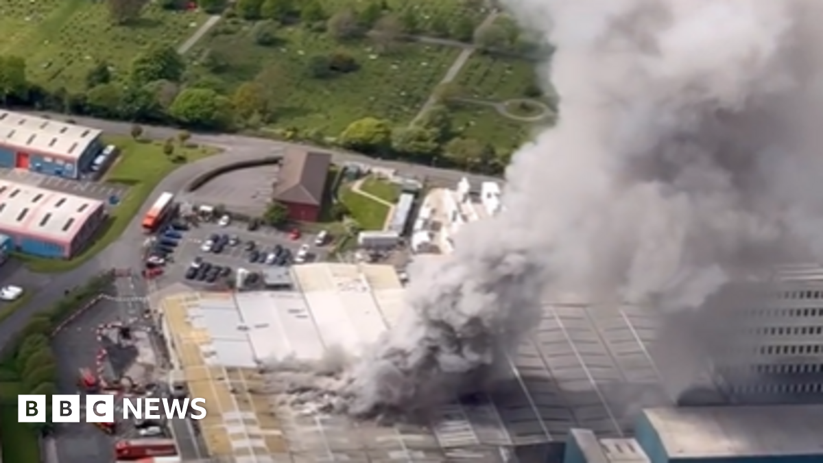 Image taken from a helicopter shows smoke rising from the Warburtons factory in Burnley. A large column on grey smoke rises from the roof the building.