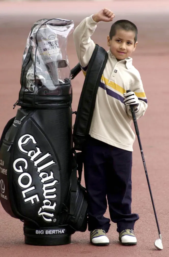 Five -year-old Aaron Rai, from Wolverhampton, holds Colin Montgomerie's golf bag at the Millennium Dome at the launch of National Golf Week. The week will give people the chance to have free golf lessons from PGA Professionals at the Dome.