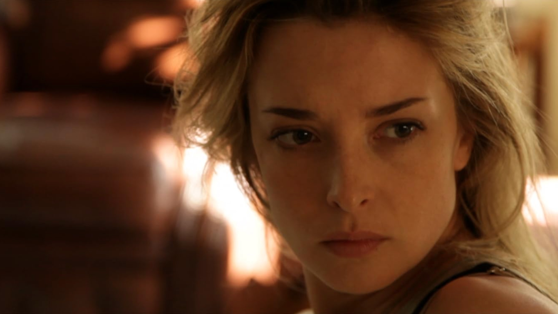 A blond woman looking intensely at something off screen behind the camera. Scene from the 2013 American science fiction psychological thriller "Coherence".