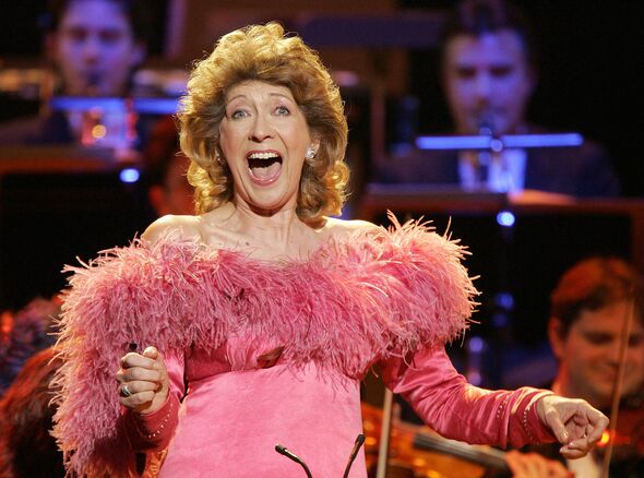 Close up of Dame Felicity Lott singing on stage - an orchestra can be seen in the background Close up of Dame Felicity Lott singing on stage - an orchestra can be seen in the background