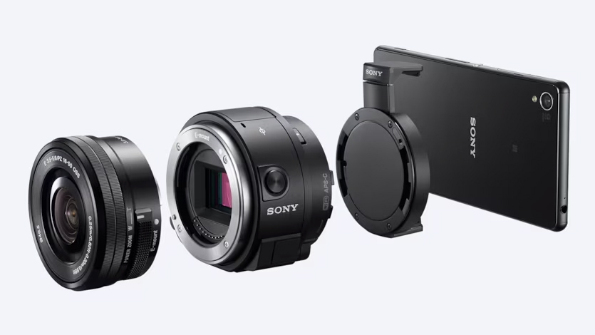 The Sony QX1 is pictured with its smartphone mount, a smartphone, and a lens on a white background