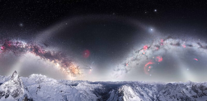 A panoramic view of snowy mountain peaks under a star-filled night sky, with the Milky Way arching across, nebulae visible, and a bright halo or arc of light spanning the starry sky.