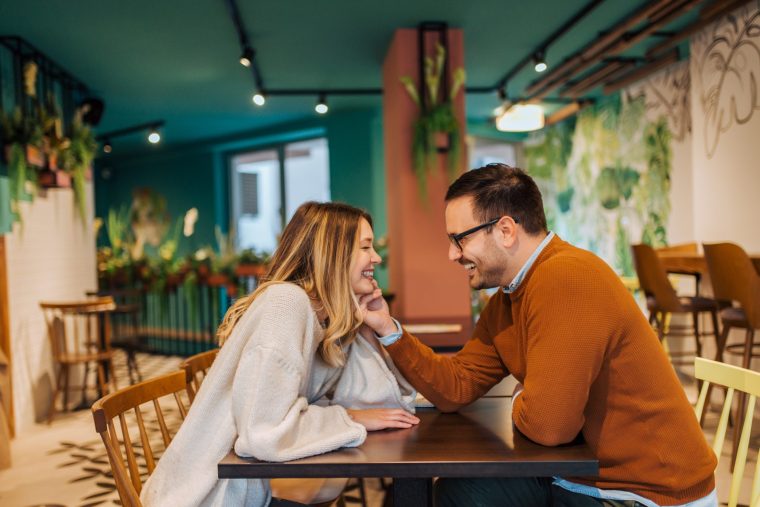 Side view of affectionate happy couple sitting in the cozy cafe. - stock photo