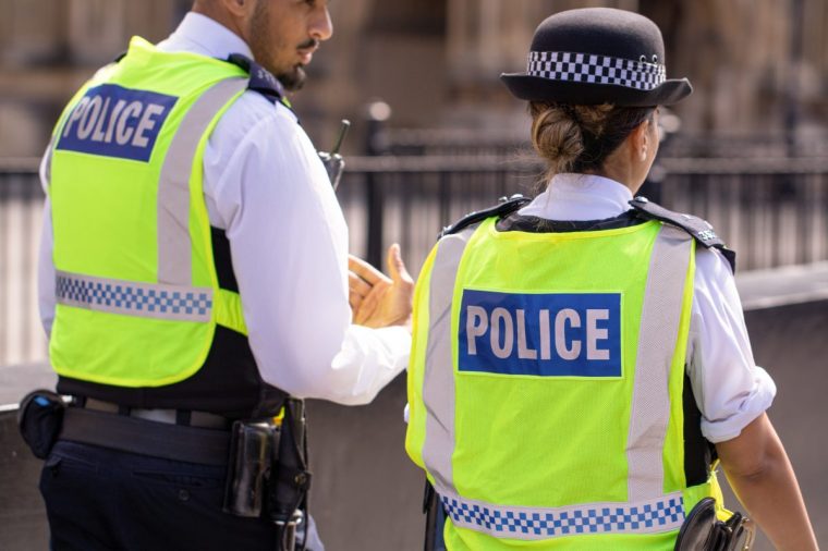 Male and female Asian metropolitan police officers patrol the crowds of tourists outside the Hoses of Parliament in Westminster, London, UK - stock photo