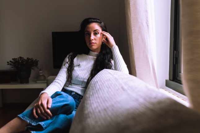 Serious young woman sitting on sofa