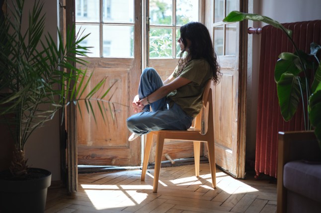 Upset lonely millennial girl looking out window, feeling sad and depressed. Female solitude, loneliness concept