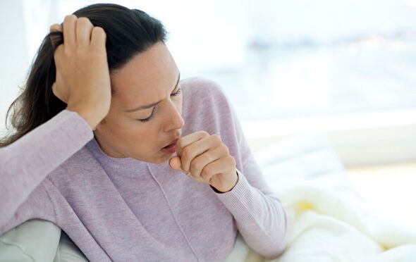 A woman wearing a lilac sweater puts a hand to her mouth as she coughs in an image posed by a model A woman wearing a lilac sweater puts a hand to her mouth as she coughs in an image posed by a model