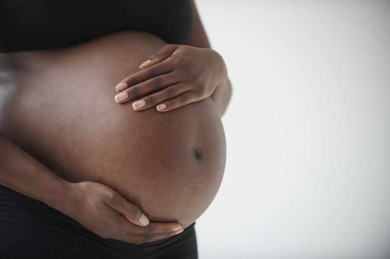 Midsection of pregnant Black woman holding belly - stock photo