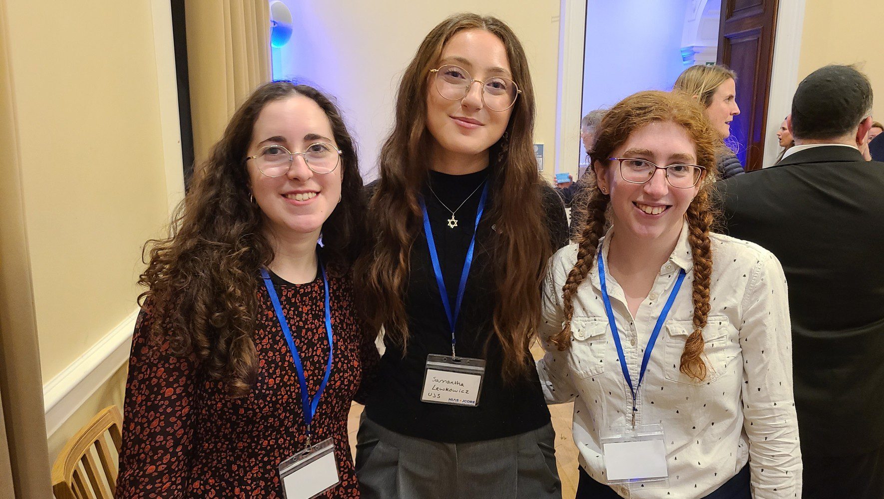 Sam (center) and Phoebe (right) are a part of HIAS+JCORE's Student Refugee Ambassador Program (SRAP). They joined refugee supporters at an event to launch Refugee Shabbat in London on March 12, 2026 (Jennie van den Boogaard/HIAS).