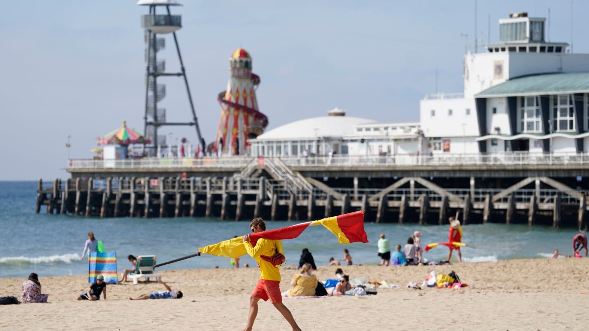 A RNLI lifeguard carrying a flag on Bournemouth beach after a 17-year-old-boy and a girl aged 12 sustained 