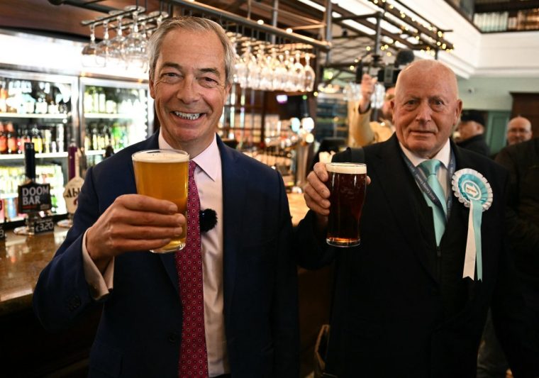 Reform UK Leader Nigel Farage and Reform candidate Trevor Shonk pose for a photograph with a pint of beer each, in a Wetherspoons pub whilst canvassing for voters ahead of local elections, in Ramsgate on the south east coast of England, on April 24, 2025. (Photo by Ben STANSALL / AFP) (Photo by BEN STANSALL/AFP via Getty Images)