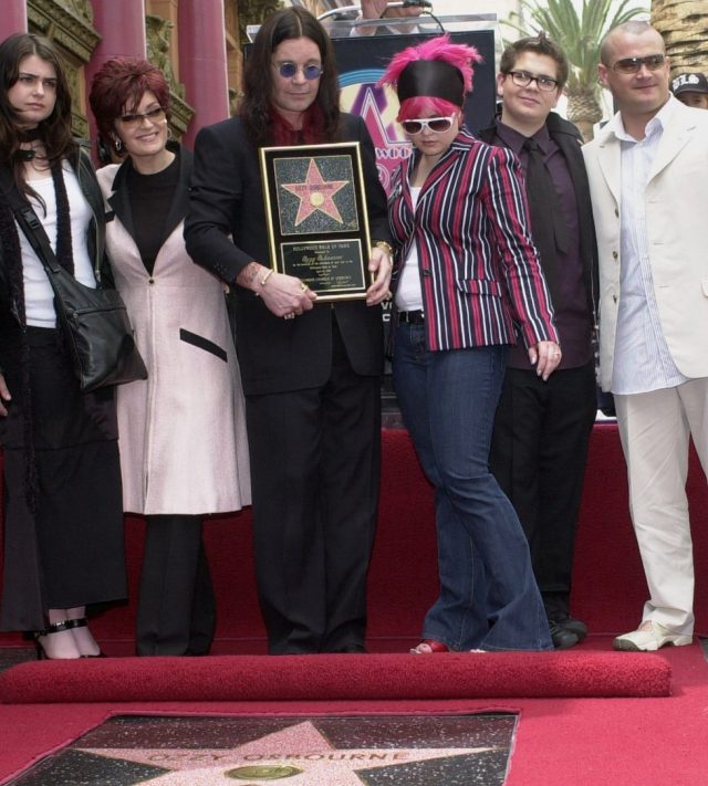 FILE - Metal-rock star Ozzy Osbourne holds a replica of his new star on the Hollywood Walk of Fame as he poses with his family during a ceremony on April 12, 2002, in Los Angeles. Pictured with Osbourne, from left, are Aimee, Sharon, Kelly, Jack and Louis. (AP Photo/Nick Ut, File)