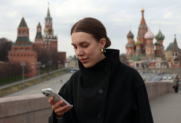 MOSCOW, RUSSIA - MARCH 31: A woman attempts to access the internet using her smartphone while walking near the Kremlin, on March 31, 2026 in Moscow, Russia. Russian authorities announced a complete block on the Telegram messaging app and the introduction of a fee for accessing international mobile internet traffic, while Apple blocked the download of VPN apps to bypass restrictions in the country. (Photo by Contributor/Getty Images)