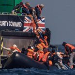 AT SEA, ENGLAND - APRIL 27: Migrants on an inflatable 'small boat' clamber on to The UK Border Force vessel, BSC Intrepid after crossing the channel from northern France on April 27, 2026 in Dover, England. Last week the UK and France signed a ??662 million, three-year deal to curb small boat crossings, featuring a first-of-its-kind ??160 million "results-based" payment conditional on a reduction in arrivals. The agreement funds a 42% increase in French coastal personnel, a new removal centre in Dunkirk, and advanced surveillance technology. While designed to disrupt smuggling gangs and secure beaches with riot-trained officers, early reports show smugglers have already begun shifting launch sites further south to bypass the intensified patrols. (Photo by Dan Kitwood/Getty Images)