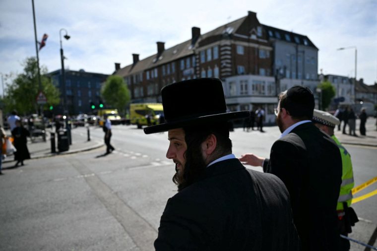 TOPSHOT - Local residents look on from outside a cordoned off area in the Golders Green neighbourhood of north London on April 29, 2026, following the stabbing to two people nearby. Two people were stabbed on April 29 in north London, Jewish groups said, following a series of arson attacks targeting Jewish sites in the area. A man was arrested after he was seen running with a knife 