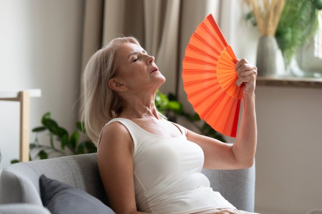 Stressed woman using waving fan suffer from overheating in the summer