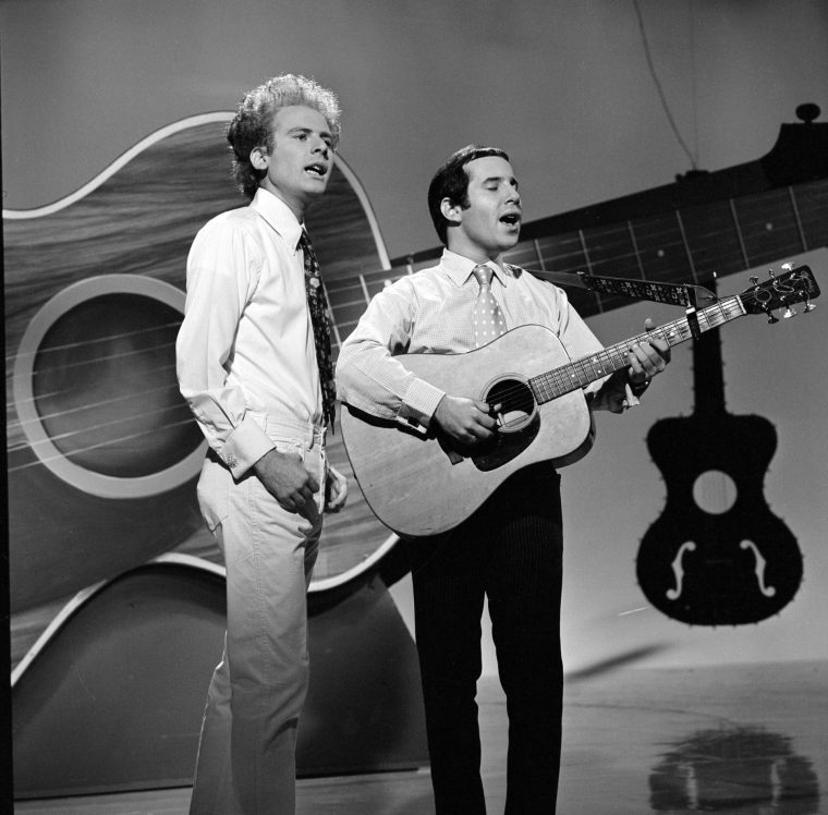 LOS ANGELES - AUGUST 22: American folk-pop musicians (from left) Art Garfunkel and Paul Simon, of the duo Simon and Garfunkel, sing and play guitar as they perform on the CBS variety program 'The Red Skelton Hour,' USA, August 22, 1966. (Photo by CBS via Getty Images)