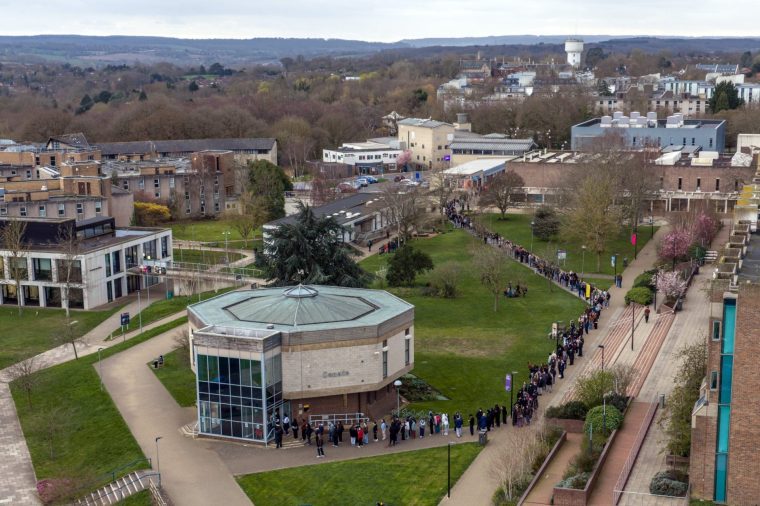 CANTERBURY, ENGLAND - MARCH 16: Staff and students, some wearing face masks, queue to receive antibiotics at the University of Kent in Canterbury after an outbreak of meningitis caused the deaths of two people, on March 16, 2026 in Canterbury, United Kingdom. A year 13 student at a grammar school in Faversham and a 21-year-old university student are confirmed to have died amid an outbreak of meningitis at the University of Kent in Canterbury. Eleven other cases have been reported since Friday. The UK Health Security Agency (UKHSA) is contacting 30,000 students and staff of the university to notify them of the outbreak. Children and young people are the most at risk of the disease, often caused by a bacterial or viral infection, which leads to inflammation of the meninges, or protective membranes around the brain and spinal cord. (Photo by Carl Court/Getty Images)