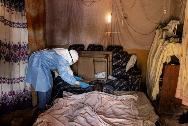 MONGBWALU, BUNIA, DEMOCRATIC REPUBLIC OF CONGO - MAY 24: (EDITOR'S NOTE: Image depicts death.) Laboratory technician Jacques Maki collects oral samples from the body of a suspected Ebola victim inside a family home in the community of Mongbwalu, after the patient reportedly died following symptoms consistent with Ebola during the outbreakon May 24, 2026 in Mongbwalu, Ituri Province, Democratic Republic of Congo. The World Health Organization (WHO) has declared the Ebola outbreak in the Democratic Republic of Congo (DRC) and Uganda a "public health emergency of international concern," as the death toll and number of confirmed cases continue to rise. The current epidemic is caused by the Bundibugyo virus, one of several Orthoebolaviruses that can cause Ebola disease, and for which there are no approved vaccines. The highest number of cases have been reported in Congo's eastern Ituri province, bordering Uganda. Global health officials have expressed grave concern over the capacity to contain the outbreak in a region already facing a humanitarian crisis, with highly mobile populations displaced by conflict and economic factors. (Photo by Michel Lunanga/Getty Images)