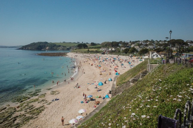 FALMOUTH, ENGLAND - MAY 26: Sunbathers gather early on on Gyllyngvase Beach, on May 26, 2026 in Falmouth, England. The UK has recoded the hottest May temperature on record with a blistering 34.8??C registered at Kew Gardens. Overnight temperatures also reached a record-breaking 21.3??C, marking the country's first-ever spring "tropical night." This extreme heatwave has triggered Amber Heat-Health Alerts across central and southern England. (Photo by Hugh R Hastings/Getty Images)