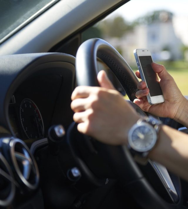 Young woman texting while driving