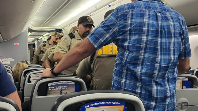 Officers walking down the aisle of a United Airlines plane.