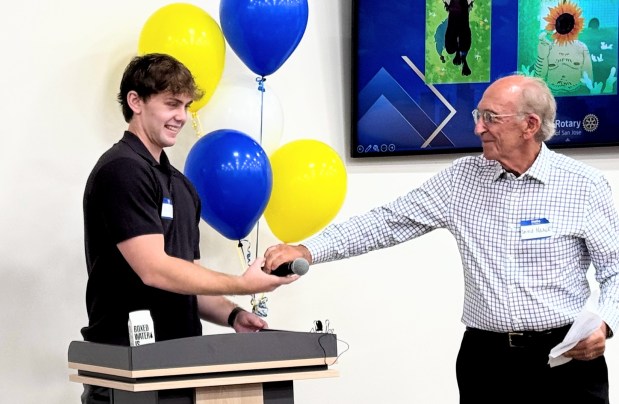 Ryan Neale receives the microphone from his grandfather, David Neale, between speeches at a celebration of neurodivergent artists sponsored by the Rotary Club of San Jose on Sunday, May 17, 2026 at the Goodwill Opportunity Center in San Jose. (Sal Pizarro/Bay Area News Group)